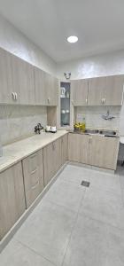 a large kitchen with wooden cabinets and a white tile floor at Al Barari Farm & Resorts Al Ain in ‘Ayn al Fayḑah