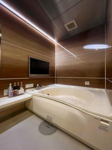 a large bathroom with a tub and a tv at ホテル アルファ in Iizaka