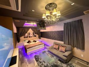 a bedroom with a bed and a couch and a chandelier at ホテルメイプル in Odate
