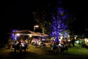 a group of people sitting at tables in a park at night at Locanda Orologio in Cormòns