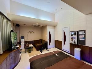 a room with a bed and a desk and a television at ホテル アルファ in Iizaka