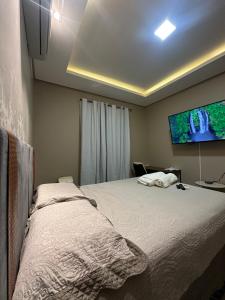 a bedroom with a bed and a flat screen tv at Conforto - Casa completa com ar-cond - Wi-Fi in Trindade