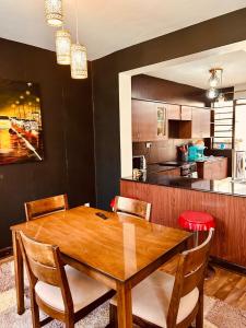 a dining room with a wooden table and a kitchen at Tranquille Homestay near JKIA Airport & SGR Station Nairobi in Nairobi