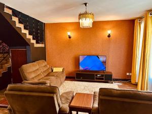 a living room with couches and a flat screen tv at Tranquille Homestay near JKIA Airport & SGR Station Nairobi in Nairobi
