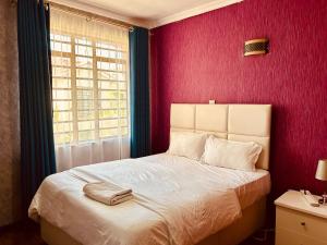 a bedroom with a white bed with a red wall at Tranquille Homestay near JKIA Airport & SGR Station Nairobi in Nairobi