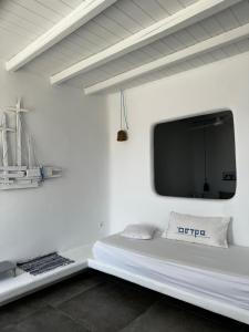 a white room with a bed with a tv on the wall at Astra Serifos in Livadi