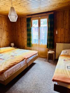 two beds in a bedroom with wooden walls and windows at Zimmervermietung Ackersand in Stalden +59 photos