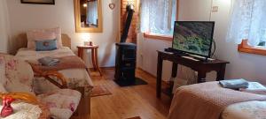 a living room with two beds and a flat screen tv at Fenyő Kuckó in Bodony