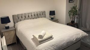 a bedroom with a bed with two towels and two lamps at 2 bed room , ensuite Flat close to Heathrow, Windsor , Langley in Langley Marish