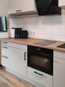 a kitchen with white cabinets and a black oven at Ferienwohnung Gessert in Querfurt +14 photos