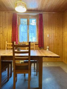 a dining room with a wooden table and red curtains at Zimmervermietung Ackersand in Stalden