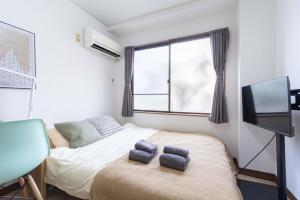 a bedroom with a bed with two towels on it at Kunark KM102 Stay in Kokubunji