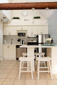 a kitchen with white cabinets and a counter with stools at Condo Loft at Blue Mountain in Blue Mountains