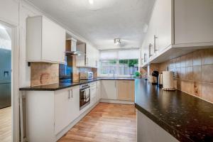 a kitchen with white cabinets and black counter tops at Spacious 4-Bed House, & Prime Location Solihull in Olton