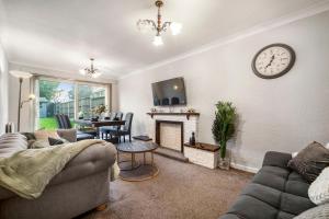 a living room with a couch and a clock on the wall at Spacious 4-Bed House, & Prime Location Solihull in Olton