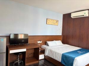 a bedroom with a bed and a desk with a television at Blue Luxury Hotel & Spa in Danang