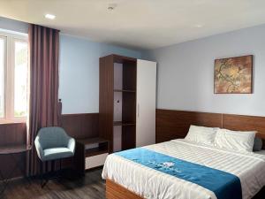 a bedroom with a bed and a chair and a window at Blue Luxury Hotel & Spa in Danang
