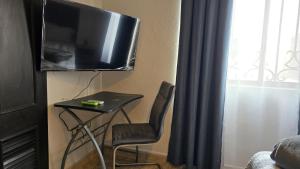 a small table with a chair and a television on a wall at Habitacion Cedro in Saltillo