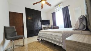 a bedroom with a bed and a chair and a television at Habitacion Cedro in Saltillo