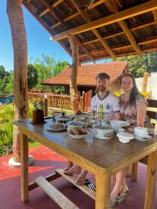 a man and woman sitting at a wooden table with food at Blue Ocean Tree House Hiriketiya in Dickwella