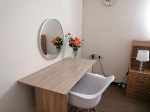 a table with a vase of flowers and a mirror at Mimosa House Double Room in Brackenfell +2 photos