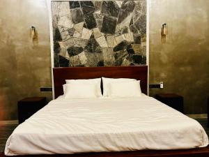 a bedroom with a white bed with a painting on the wall at Villa Stillrock in Dodanduwa