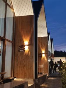 a building with a wooden wall with lights on it at Pijar Jingga Cabin in Diyeng