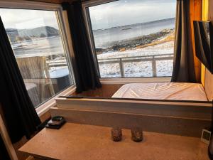 a bedroom with a bed and two large windows at Unik og moderne microhytte med utsikt mot havet 40 A Otterlei Resort in Longva