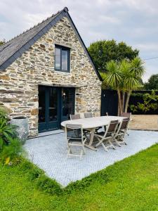 a table and chairs in front of a stone house at Dépendance chez l'habitant in Morlaix