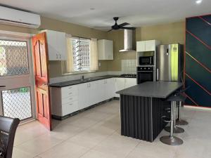 a kitchen with white cabinets and a black counter top at Secure Vailima Home with Fale in Apia