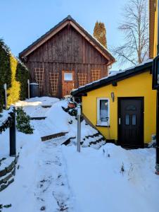 a yellow building with snow on the ground at Ferienwohnung Hähnert in Schwarzenberg +11 photos