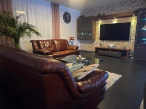 a living room with leather furniture and a flat screen tv at Haus Moor Merland in Moormerland