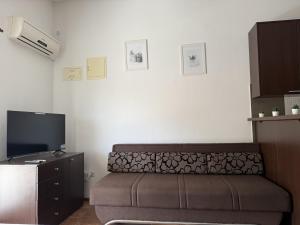 a living room with a couch and a flat screen tv at Apartments Edita in Rogoznica