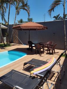 a pool with a table and an umbrella next to a pool at Edícula 55m2, aceita pequenos pets in Foz do Iguaçu