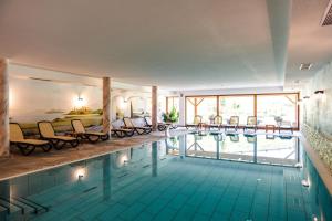 ein Hotelpool mit Stühlen und einem Bett in der Unterkunft Hohe Gaisl in Prags
