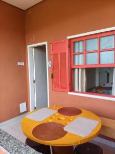 a wooden table in a room with a red window at Pousada Alforria Lavras Novas centro in Lavras Novas