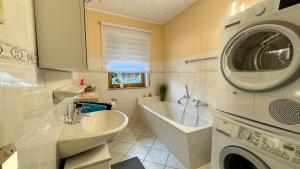 a bathroom with a sink and a washing machine at Ferienhaus RENA mit Pool in Bischdorf