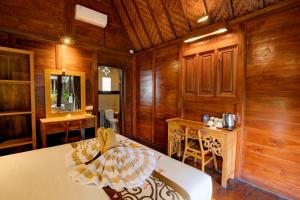 a room with wooden walls and a bed and a desk at Dupa Ubud in Ubud