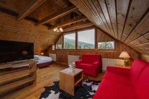 ein Wohnzimmer mit roten Möbeln, einem Bett und einem Fernseher in der Unterkunft Hohe Gaisl in Prags