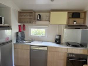 a small kitchen with wooden cabinets and a sink at Mobilhome 642 3 chambres Siblu La Réserve in Gastes