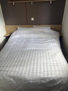 a bed with a white comforter and two pillows at Mobilhome 642 3 chambres Siblu La Réserve in Gastes