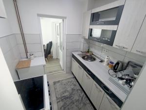 a small white kitchen with a sink and a microwave at Apartman Alić in Vogošća