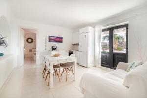 a white living room with a table and a kitchen at Princess Villas Oasis Mykonos in Kalafatis