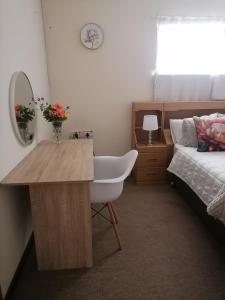 a bedroom with a bed and a desk with a white chair at Mimosa House Double Room in Brackenfell