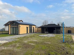 a house with a black roof and a tent at Pniówek Chill in Zamość