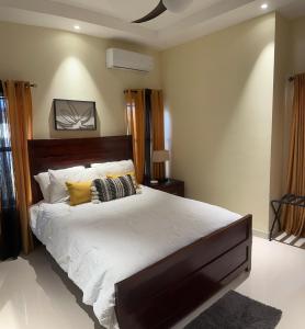 a bedroom with a large bed with white sheets and yellow pillows at Serenity Villas in Ocho Rios +34 photos