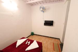 a white room with a red bed and a flat screen tv at Vayuvana Heritage Organic Farm Resort in Panamaram