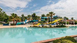 a swimming pool with a water slide in a resort at Vias plage "MER & SOLEIL" Mobil home camping La Carabasse 6 a 8 personnes in Vias