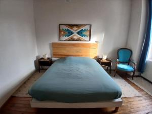 a bedroom with a bed and a blue chair at Avol d'Oiseau in Villers-Farlay