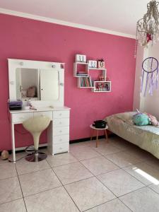 a bedroom with a white desk and a pink wall at Piso Céntrico Maipú in Maipú